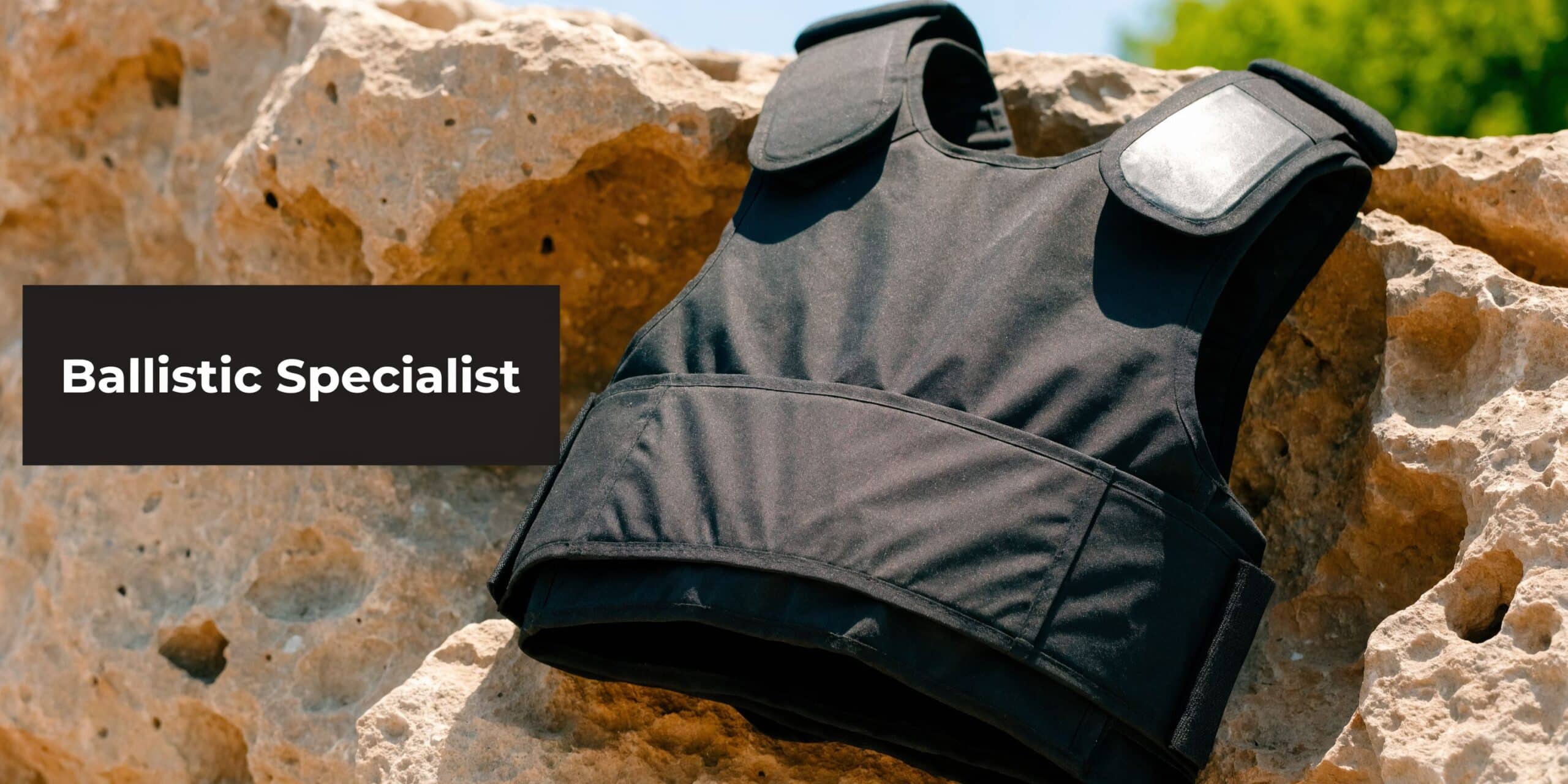 A black protective ballistic vest resting on top of a jagged, light brown natural rock formation.